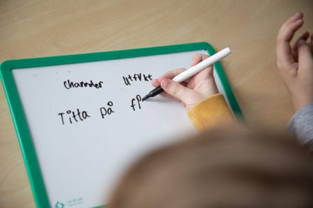 Barn skriver med på liten whiteboard tavla