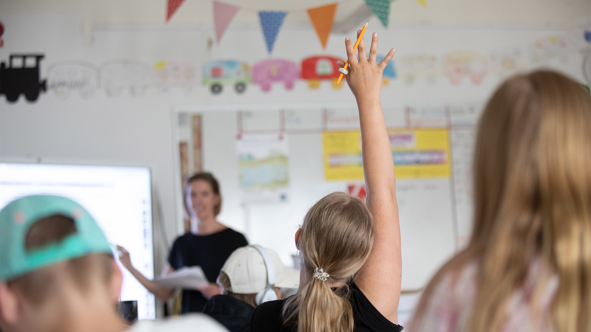 Elev räcker upp handen i en klassrumsmiljö