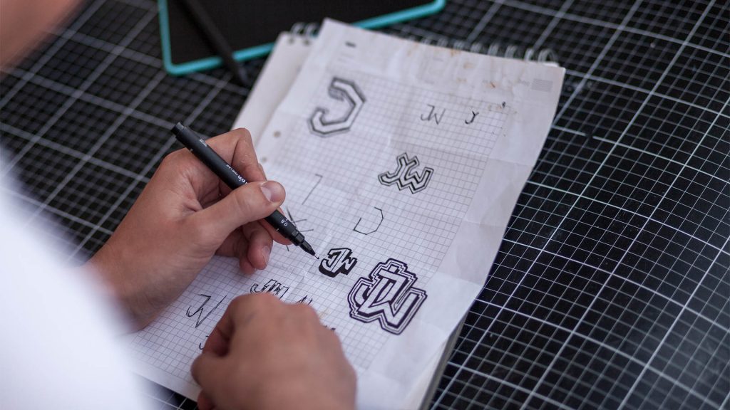 Person ritar logotyper av initialerna "JW"