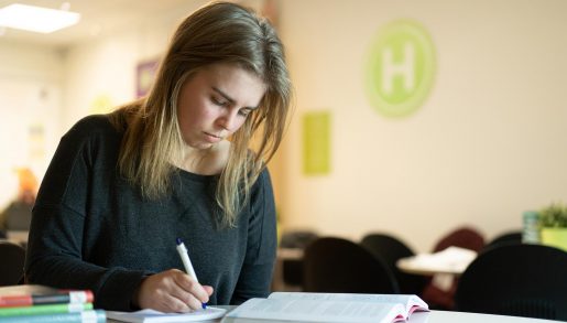 En elev på Hermods skriver anteckningar medan hon läser bok